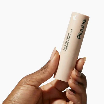 Hand holding Pluune Scar Solutions Silicone Scar Stick against a white background